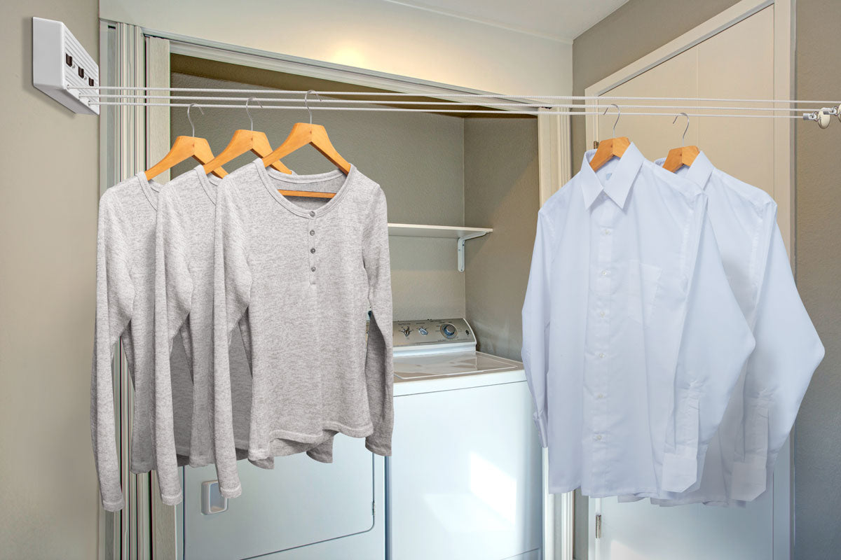 Camisas colgadas de las líneas extendidas de un tendedero retráctil en un clóset de lavado