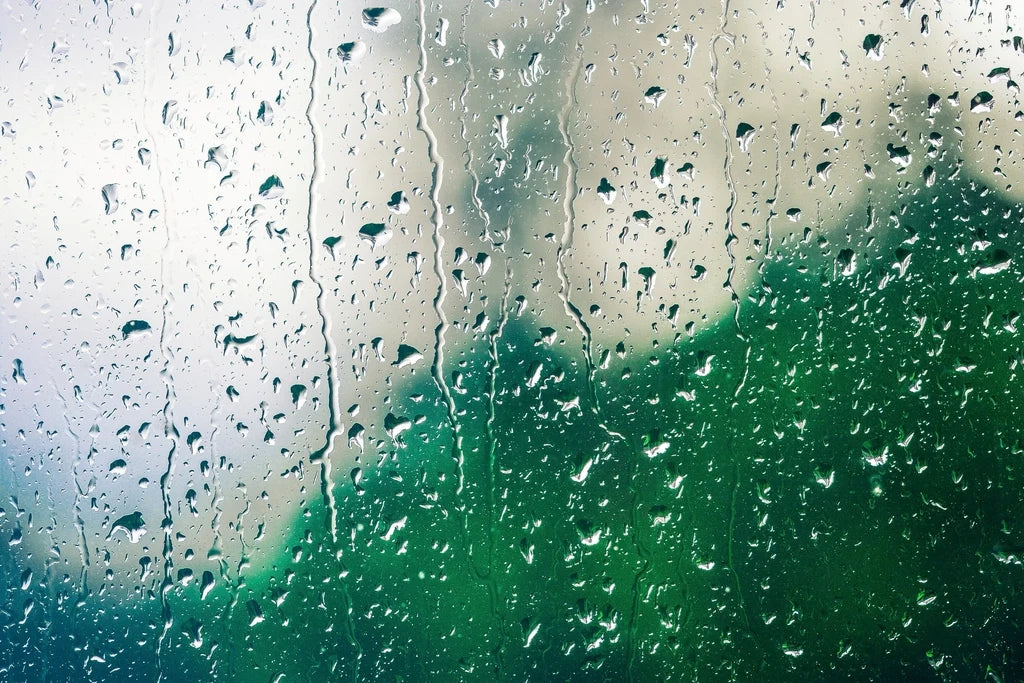 Gotas de lluvia escurriendo por el vidrio de una ventana en un día nublado